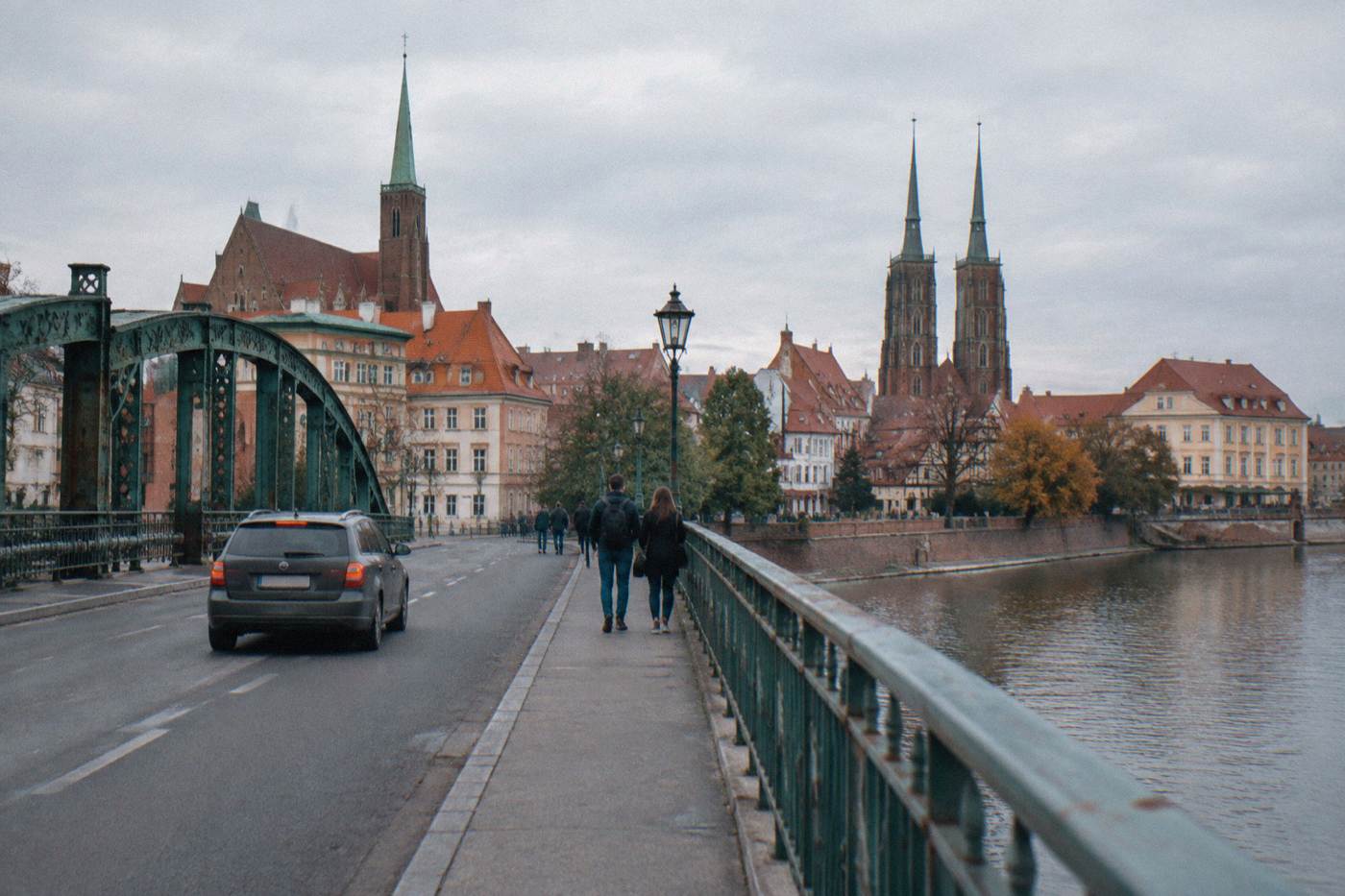 A car crossing a bridge over the Odra river toward the church towers of Wroclaw's old town