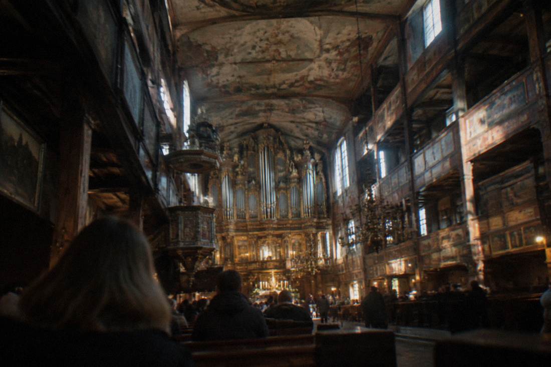The timber interior of a large historic church with galleries and painted ceilings