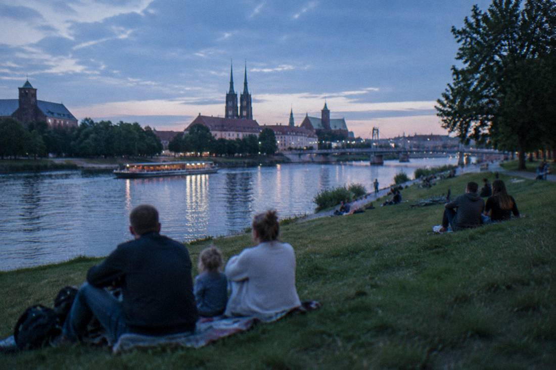 Families relaxing on the grassy banks of Slodowa Island by the Odra river