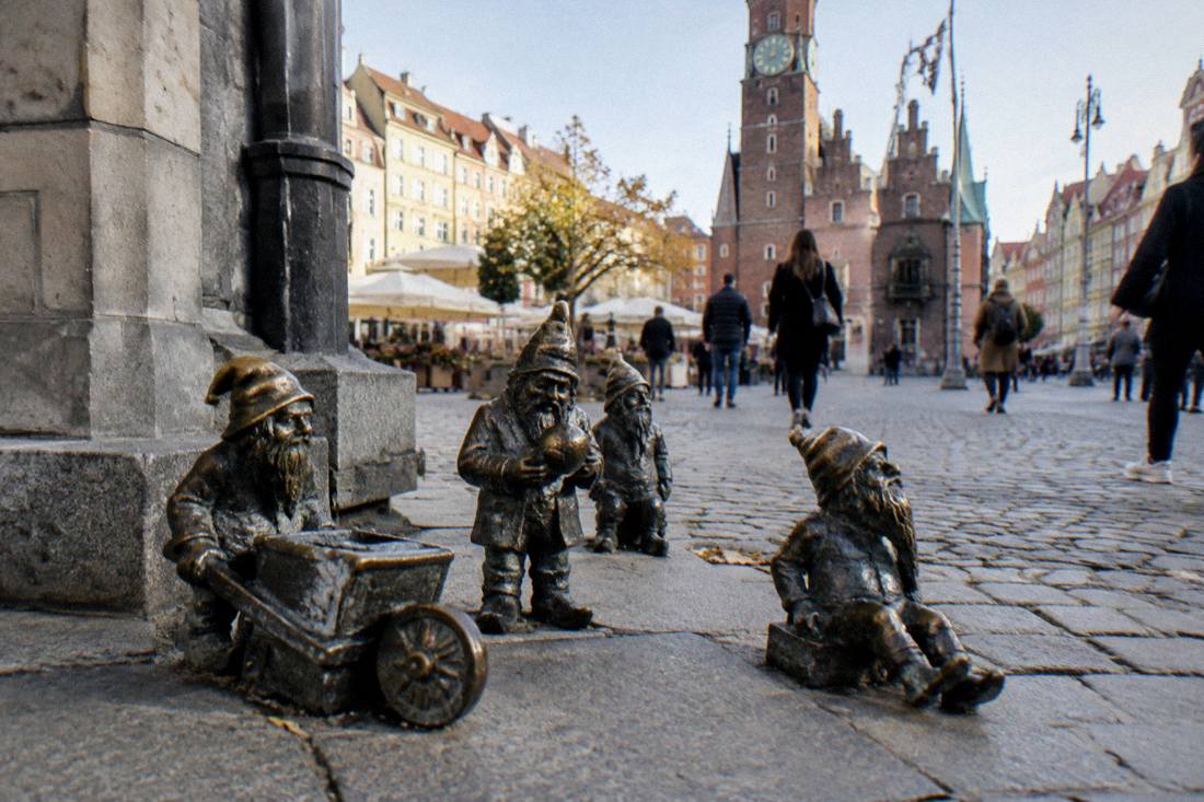 Bronze dwarf figures clustered on a sidewalk near Wroclaw Market Square