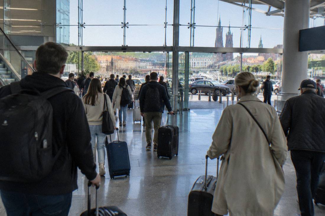 Travelers with suitcases walking through the arrivals area of a modern airport terminal