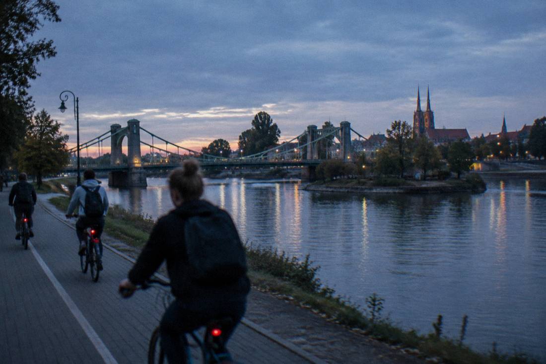 Cyclists riding along a riverside path beside the Odra river in Wroclaw