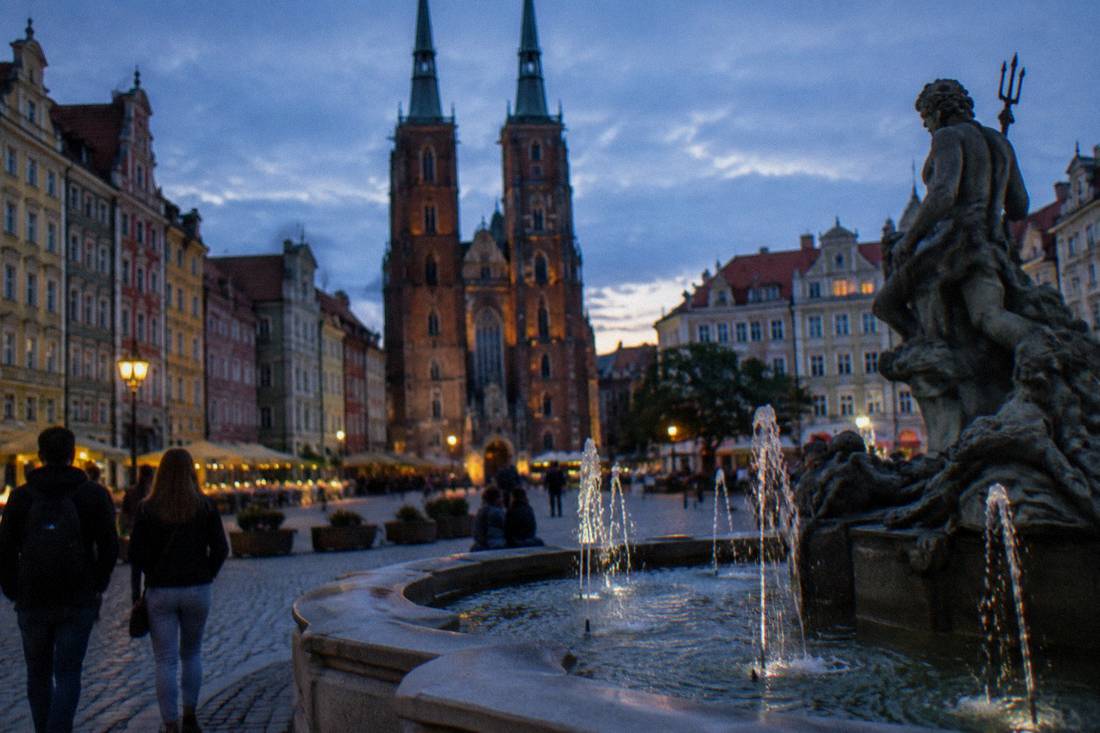A decorative stone fountain in a Wroclaw square with water jets in its basin