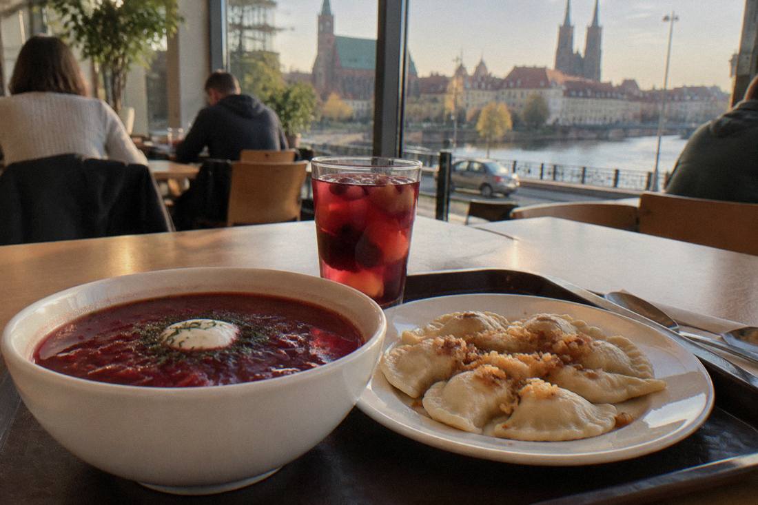 A close view of a cafeteria tray with a bowl of red soup, a plate of dumplings and a glass of kompot fruit drink
