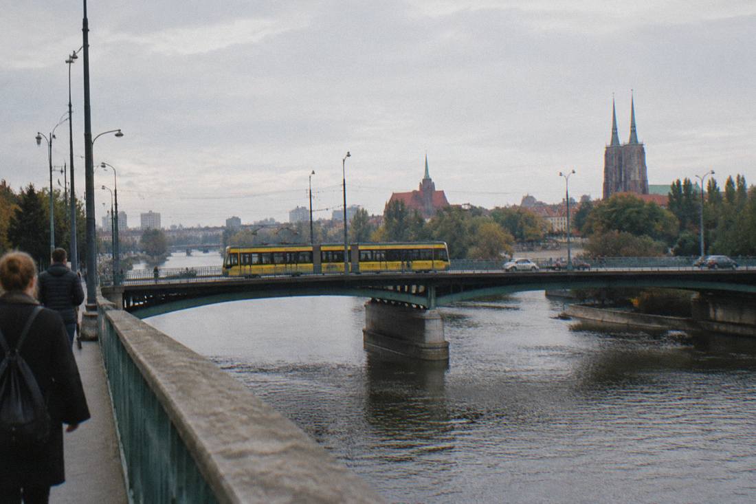 A yellow tram crossing a bridge over the Odra river in central Wroclaw