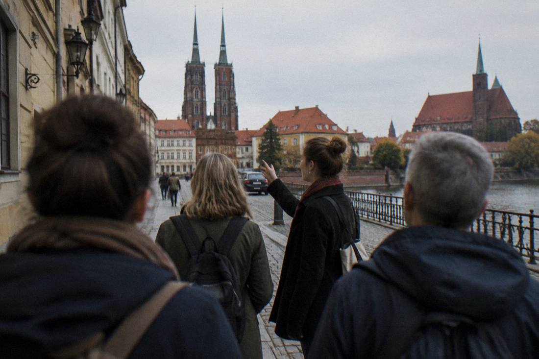 A local guide leading a small group of visitors through a Wroclaw old town street near the river