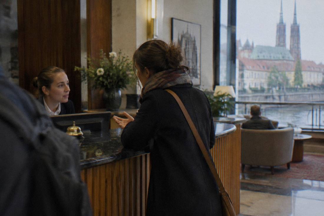 A visitor asking a question at a hotel reception desk in Wroclaw
