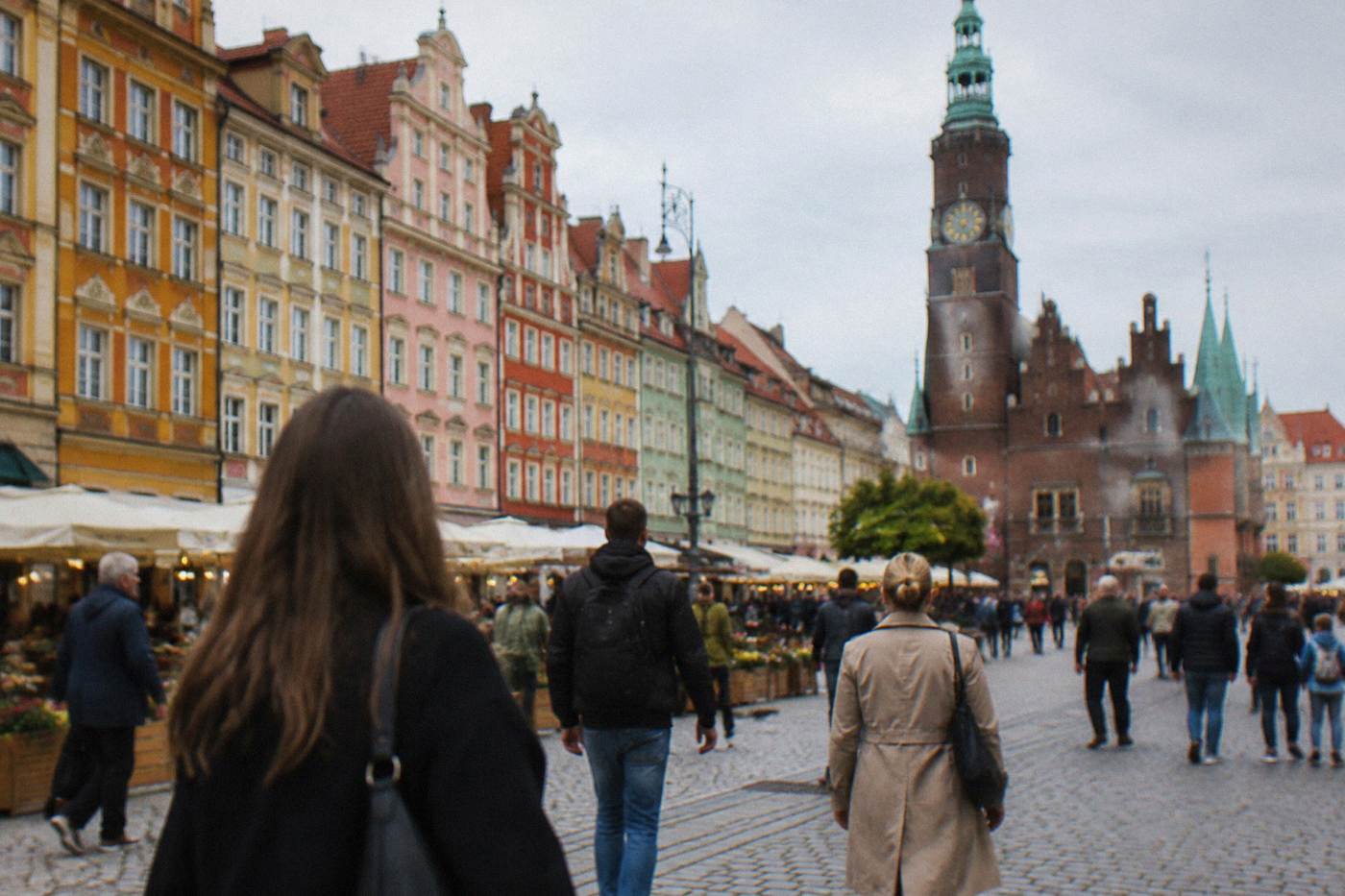 Shoppers walking past colorful townhouse facades on the market square in Wroclaw