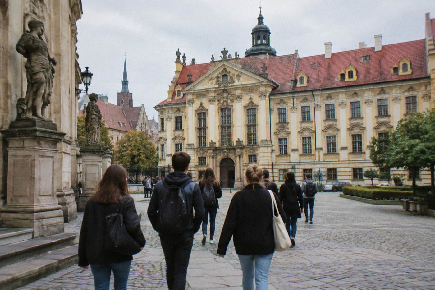Students walking across a historic university courtyard in Wroclaw with baroque facades in the background