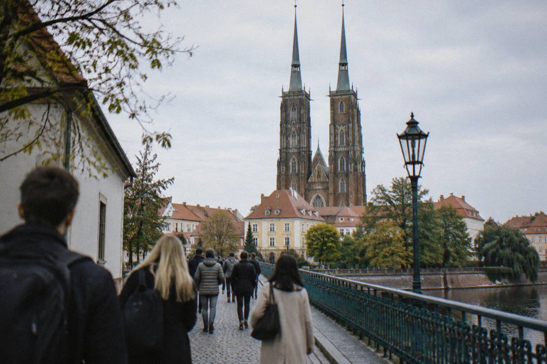 A group of visitors walking across Cathedral Island in Wroclaw with the twin spires behind