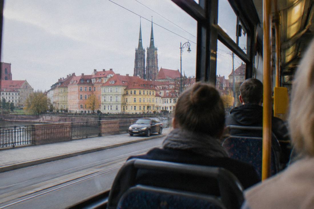 Travelers on a tram in central Wroclaw passing pastel buildings