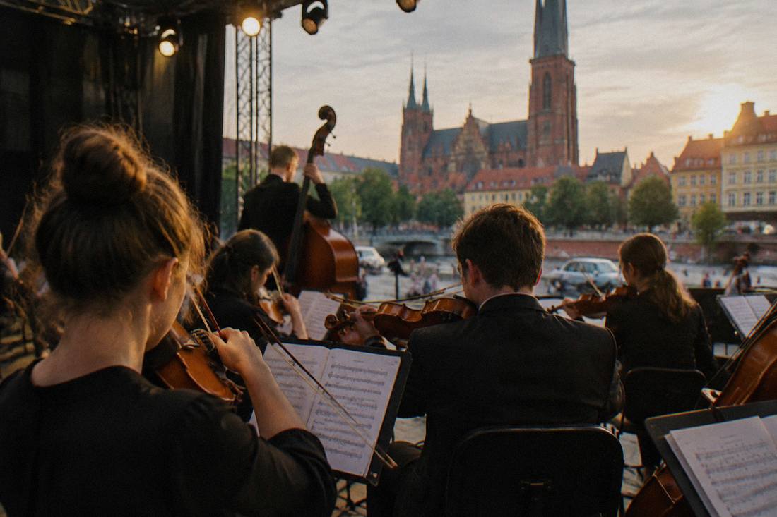 Strings section tuning instruments under stage lights before a concert