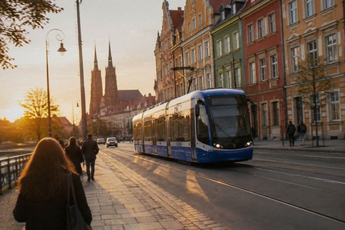 A modern tram moving along a street lined with colorful townhouses