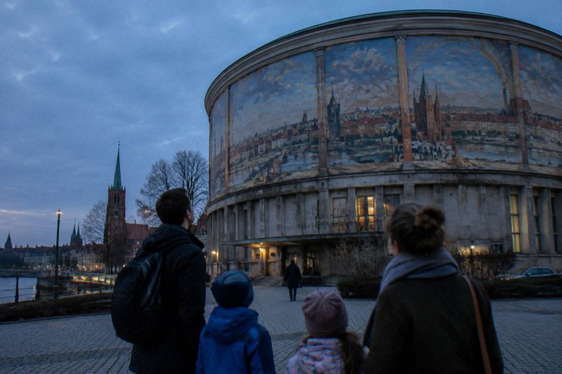 A family with children looking up at a large painted museum rotunda