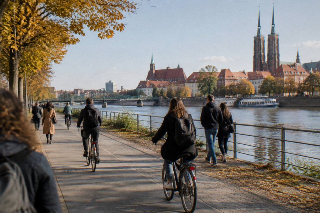Cyclists and pedestrians on a flat riverside path beside the Odra in Wroclaw