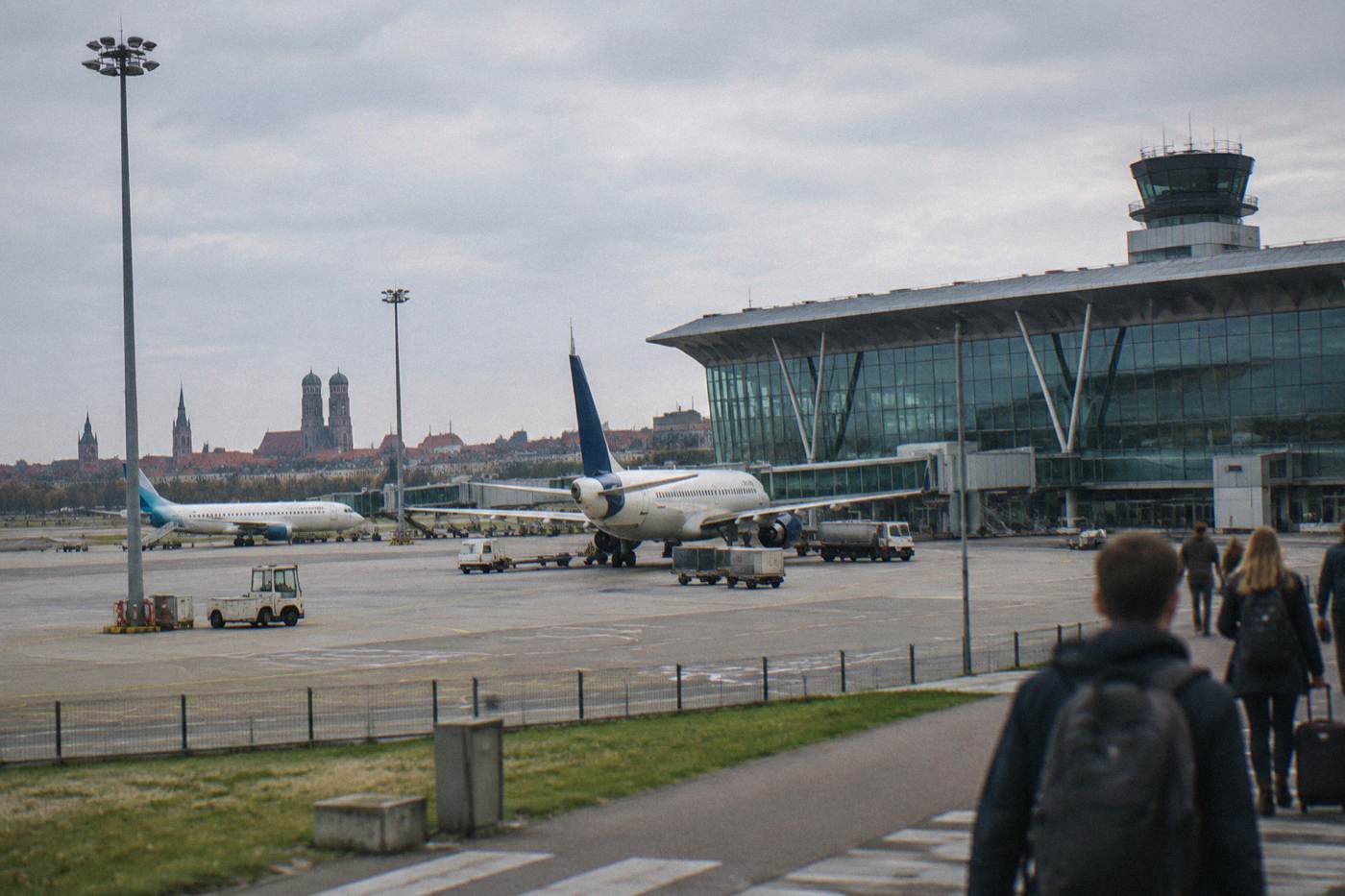 A modern airport terminal building with glass facade and parked airplanes under a daytime sky