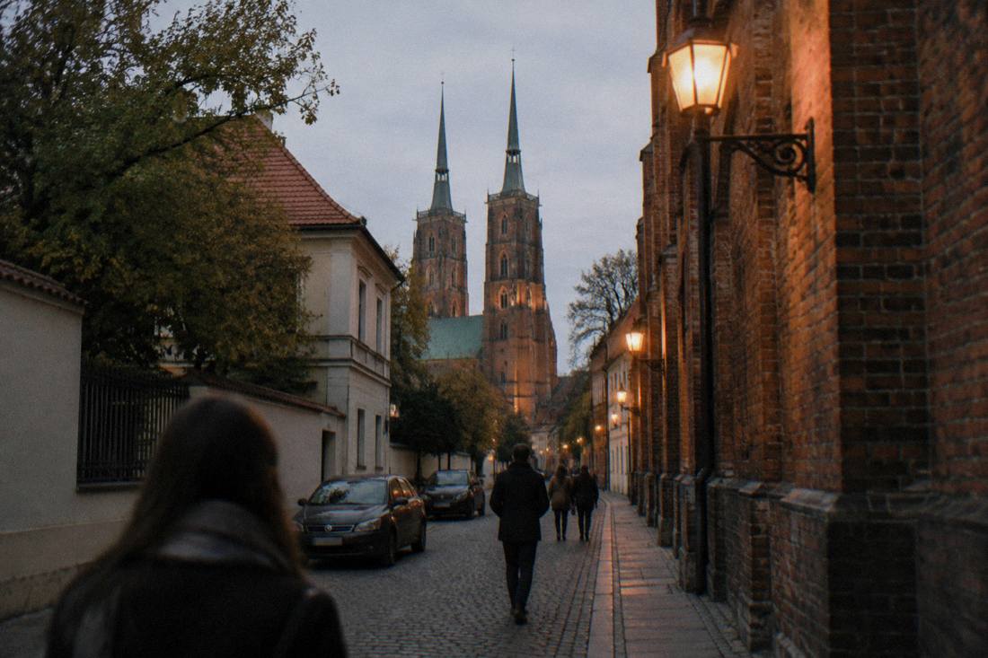 A narrow old street on a cathedral island at dusk with lanterns lit along the walls