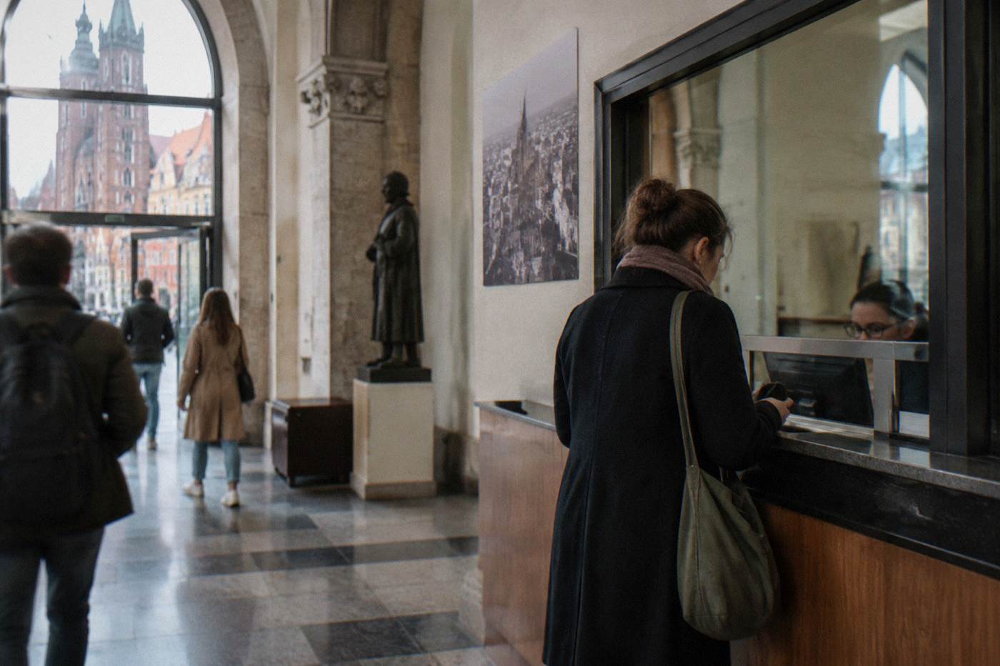 Ticket office window in a Wroclaw museum lobby with a visitor buying an admission ticket