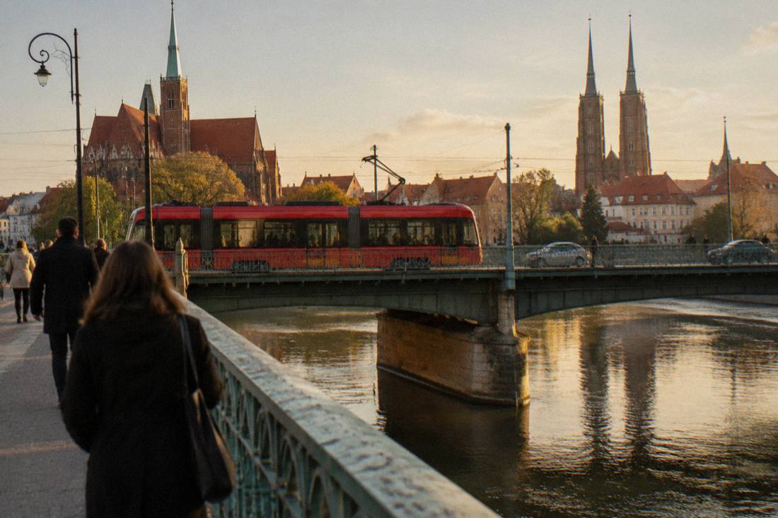 A red Wroclaw tram crossing a bridge over the Odra river in the city center