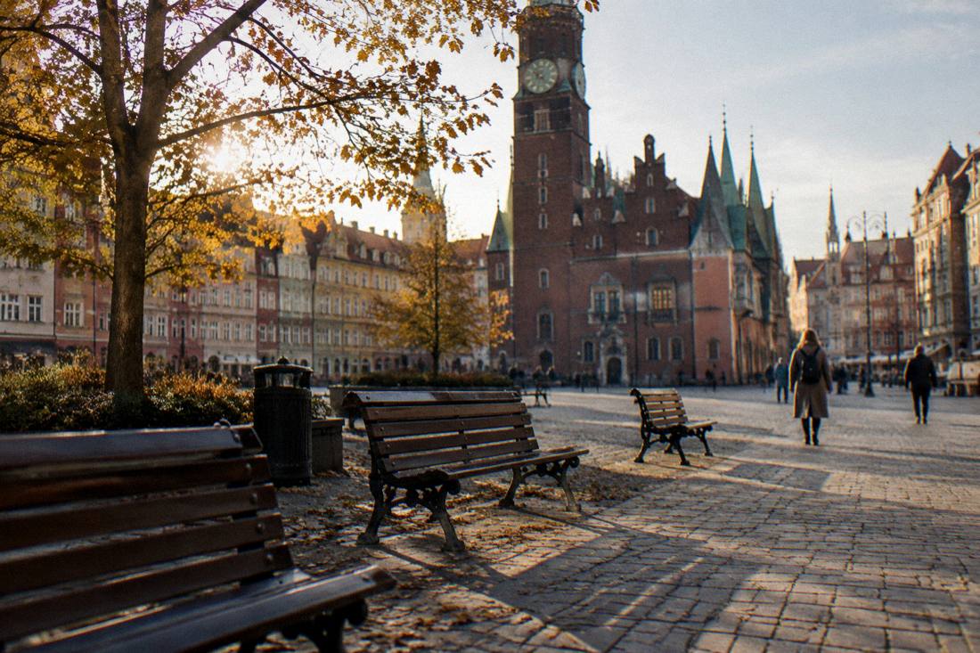 An empty terrace with wooden benches on a Wroclaw square in autumn afternoon light