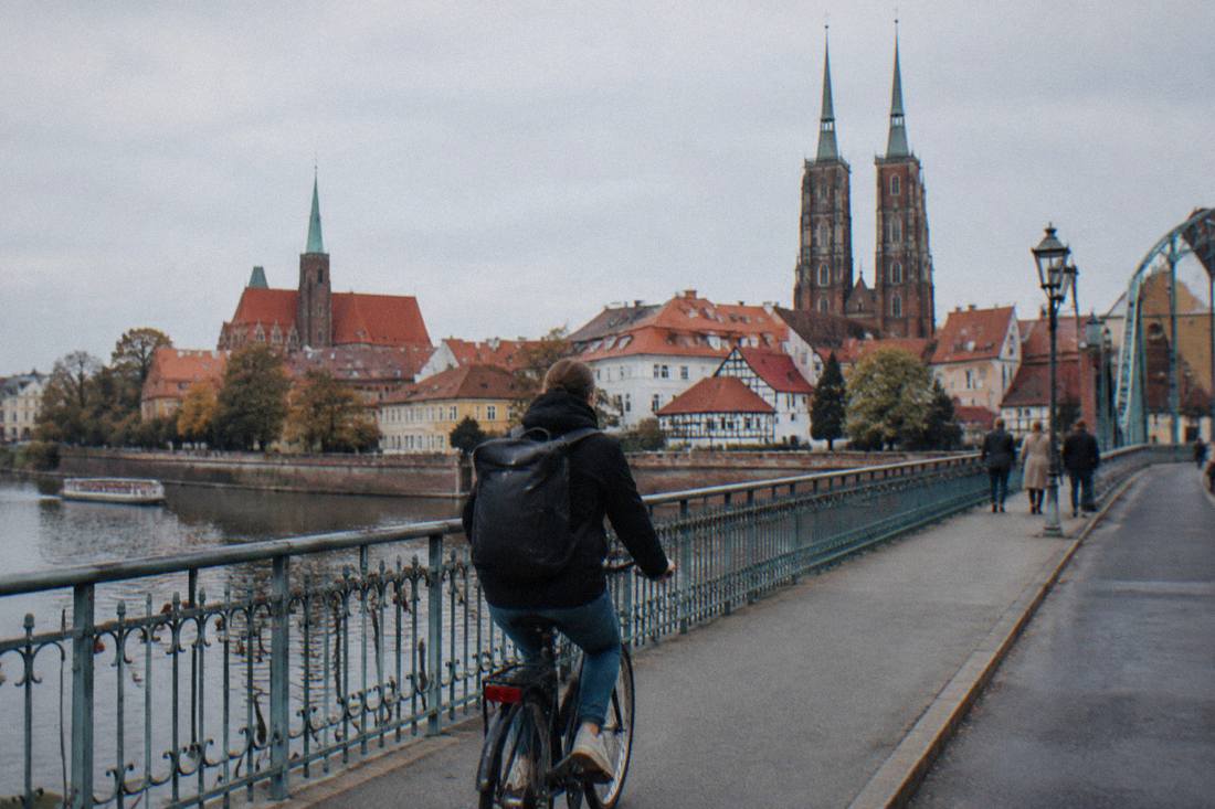 A cyclist crossing a bridge over the Odra river toward Wroclaw's old town