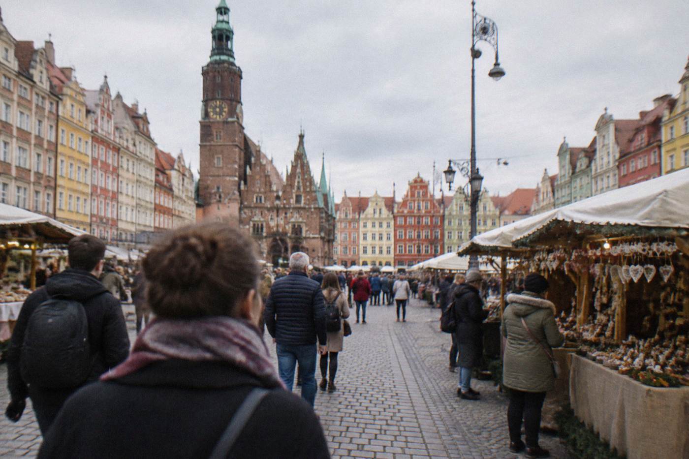 Stalls and visitors on a wide historic market square lined with colorful facades
