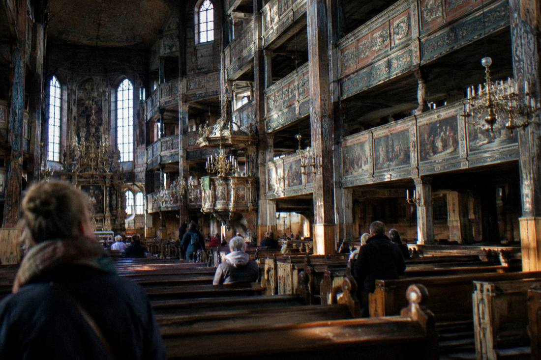 A vast timber church interior with painted galleries and wooden columns