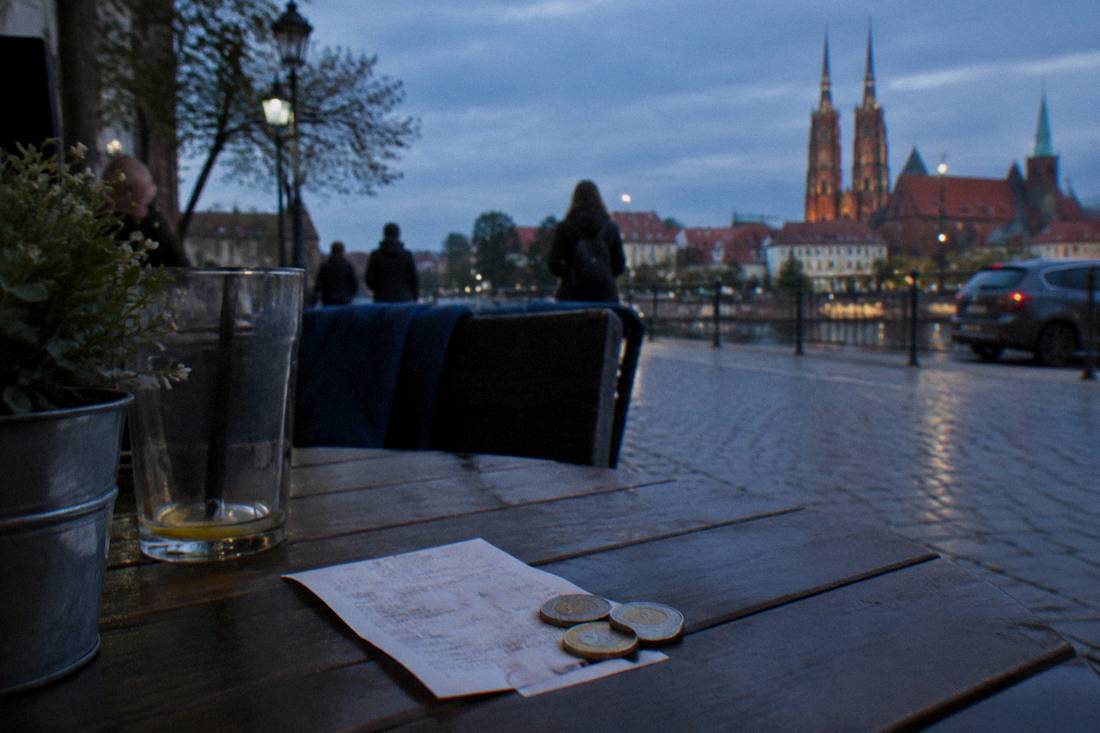 A restaurant receipt and a few zloty coins left on a table after a meal