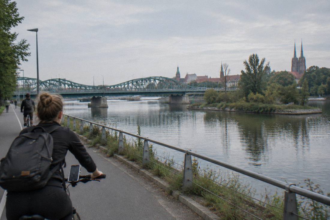A cyclist with a smartphone mounted on the handlebars riding beside the Odra river in Wroclaw