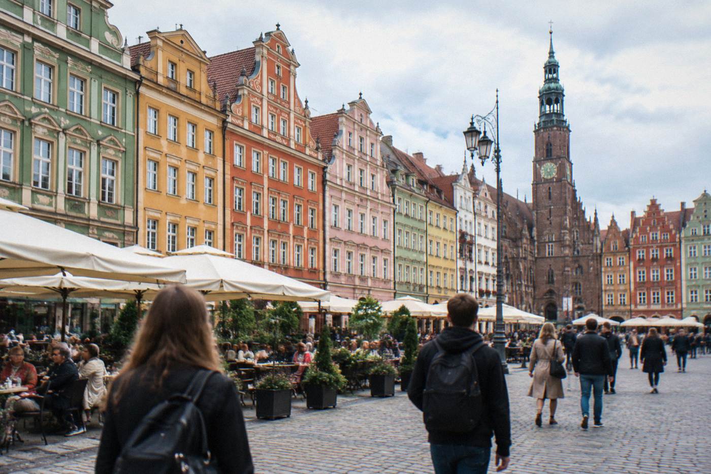 The colorful facades of Wroclaw Market Square on a bright day with cafes and people in front