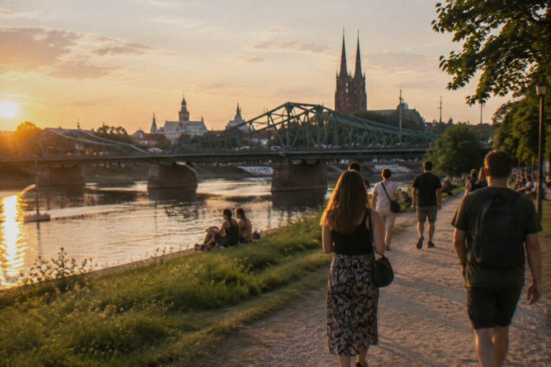 Visitors walking along a riverside path on one of Wroclaw's Odra river islands in summer