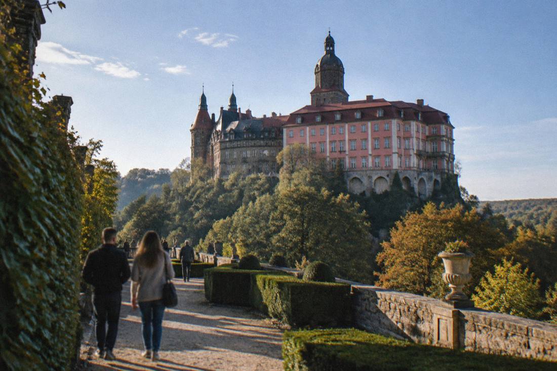 The large hilltop mass of Ksiaz Castle seen from its gardens under a blue sky