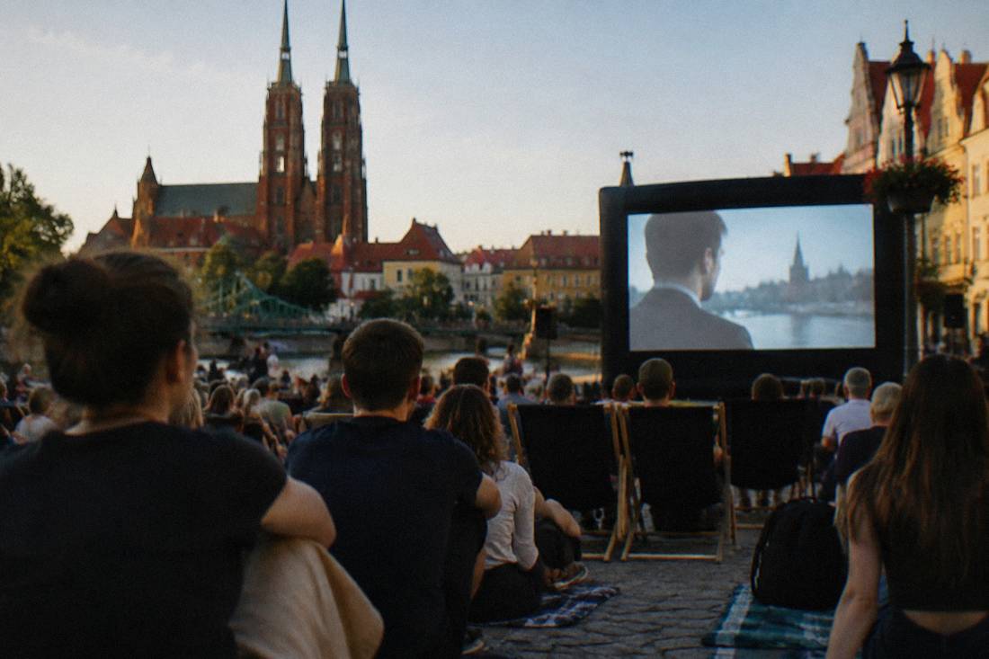 Audience members watching a film screening outdoors on a warm Wroclaw evening