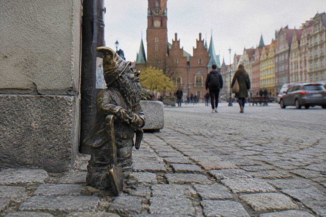 A small bronze dwarf statue on a cobblestone street in Wroclaw