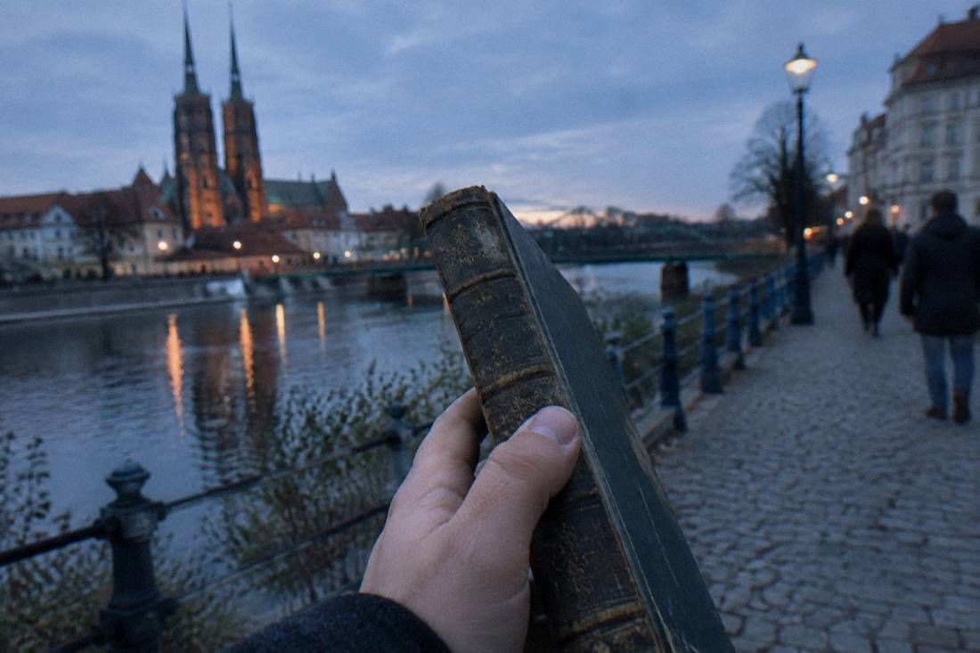 A close-up of a hand examining the worn spine of an old hardcover book