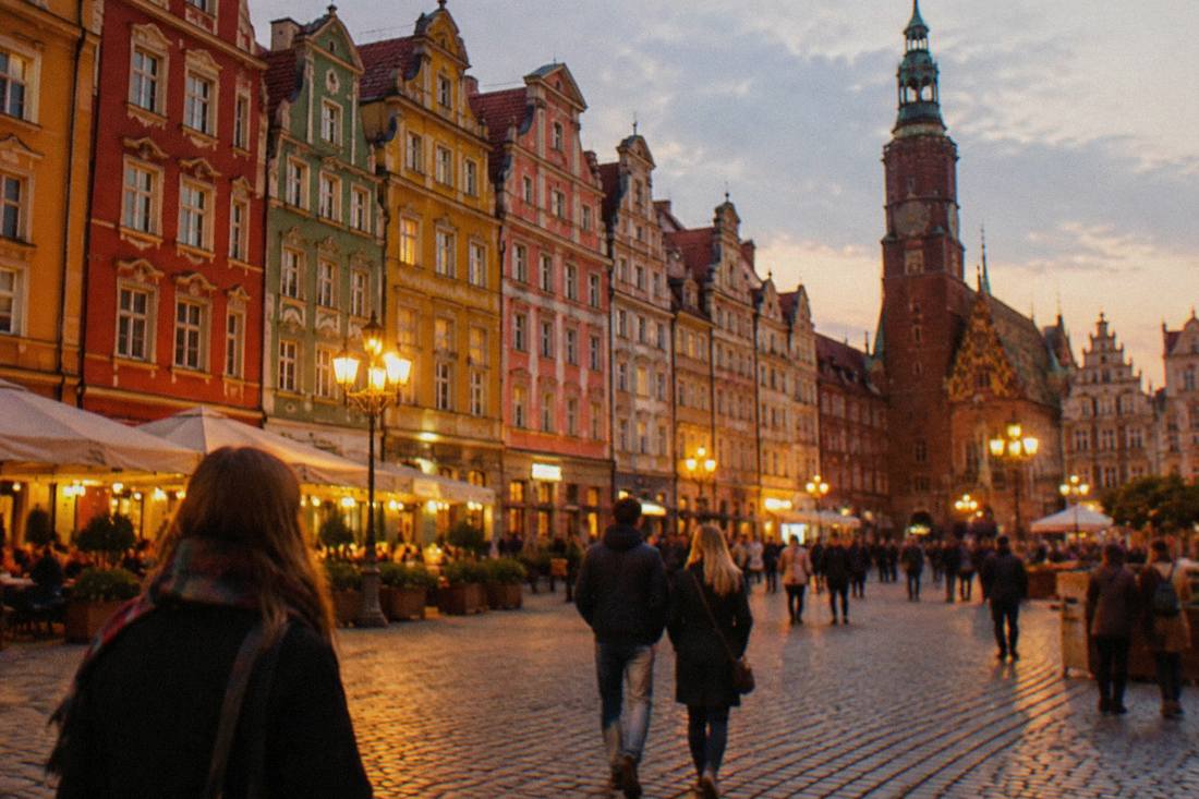 Colorful narrow townhouses glowing under lantern light on a cobbled market square