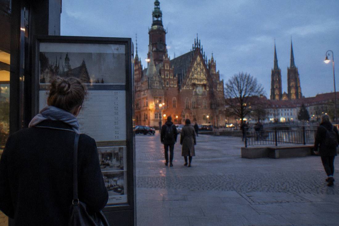 A visitor reading a museum ticket board in Wroclaw