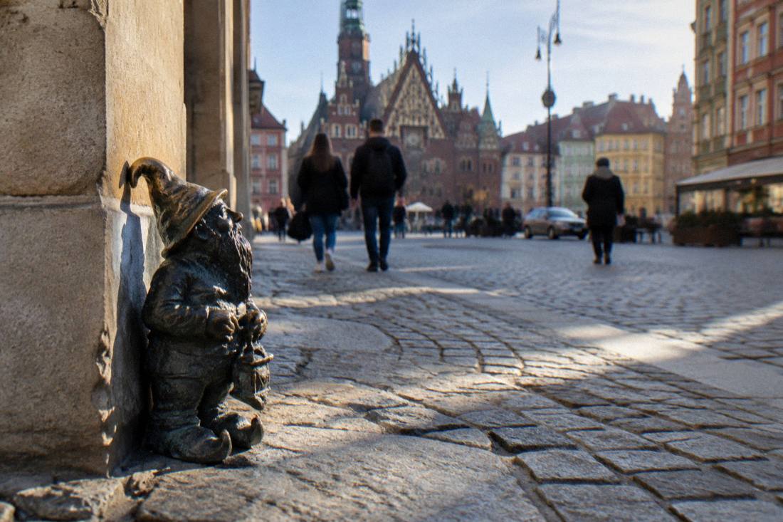 A small bronze dwarf figurine mounted on a street corner in Wroclaw's old town