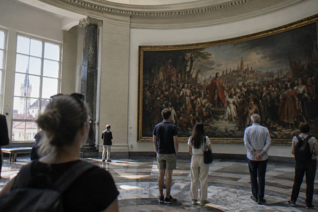 Visitors viewing a large historic painting inside a museum rotunda in Wroclaw