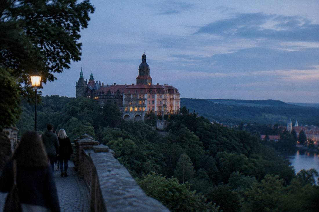 A large baroque castle on a hill above forested valleys in Lower Silesia, Poland