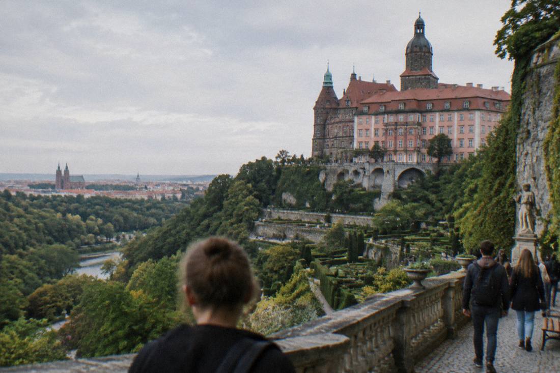 A large hilltop castle with terraced gardens overlooking a forested valley