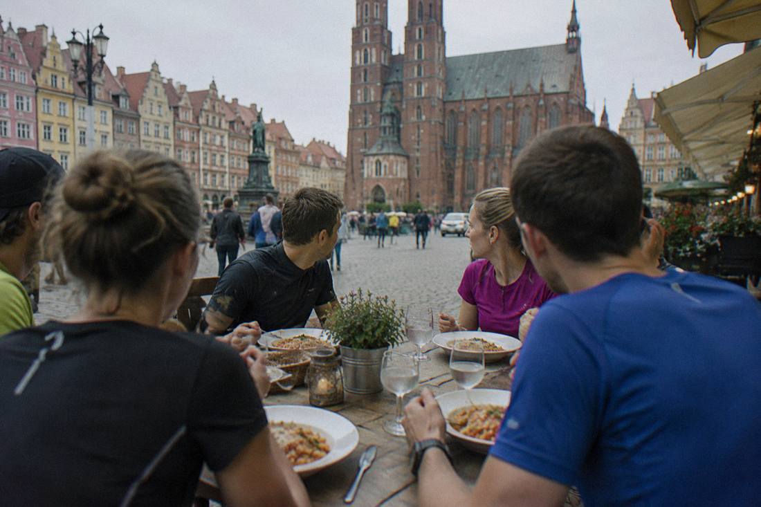 A table of runners eating a pasta dinner together at a restaurant in the Wroclaw old town.