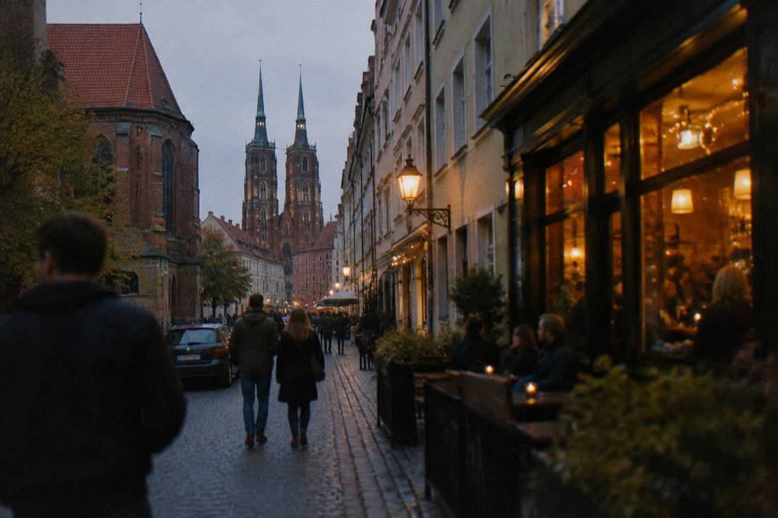 A narrow street with bars and glowing windows in the evening