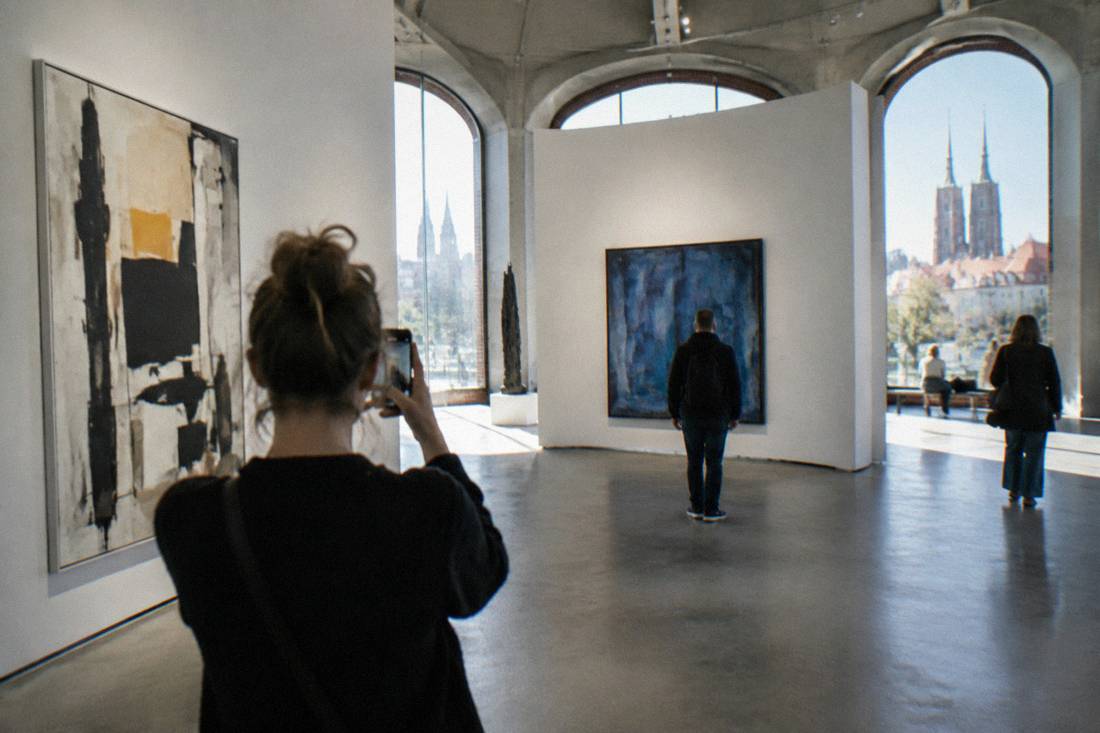 The interior of the Four Domes Pavilion in Wroclaw with a visitor photographing modern art gallery walls