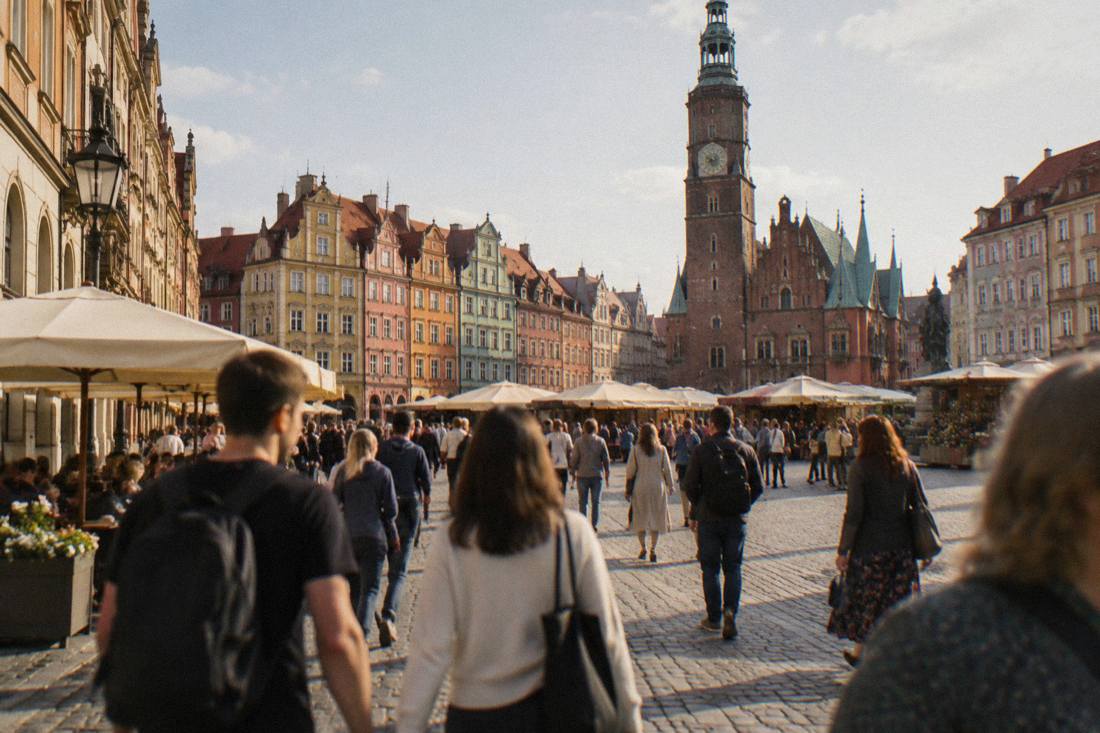 A busy market square in Wroclaw surrounded by colorful townhouses at midday