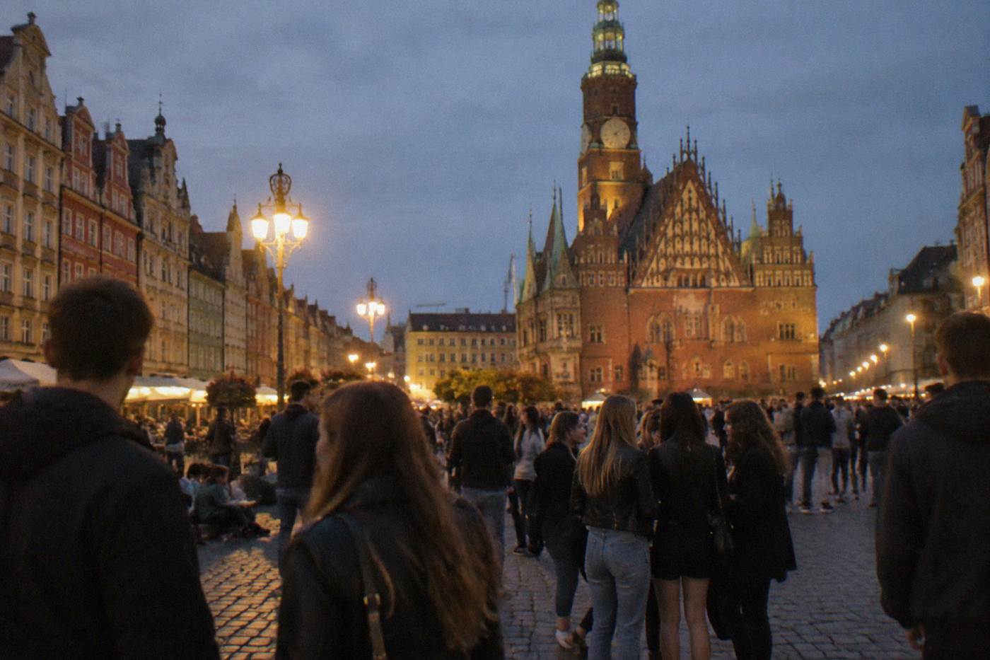 Crowds of young people gathered in a lit square in Wroclaw at night