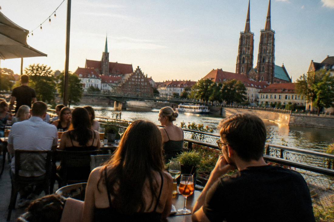 A busy outdoor terrace in Wroclaw on a warm evening with drinks on tables
