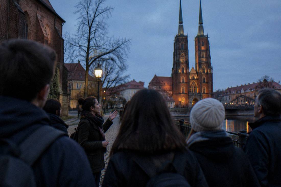 A walking tour group listening to a guide beside the cathedral on Ostrow Tumski in Wroclaw