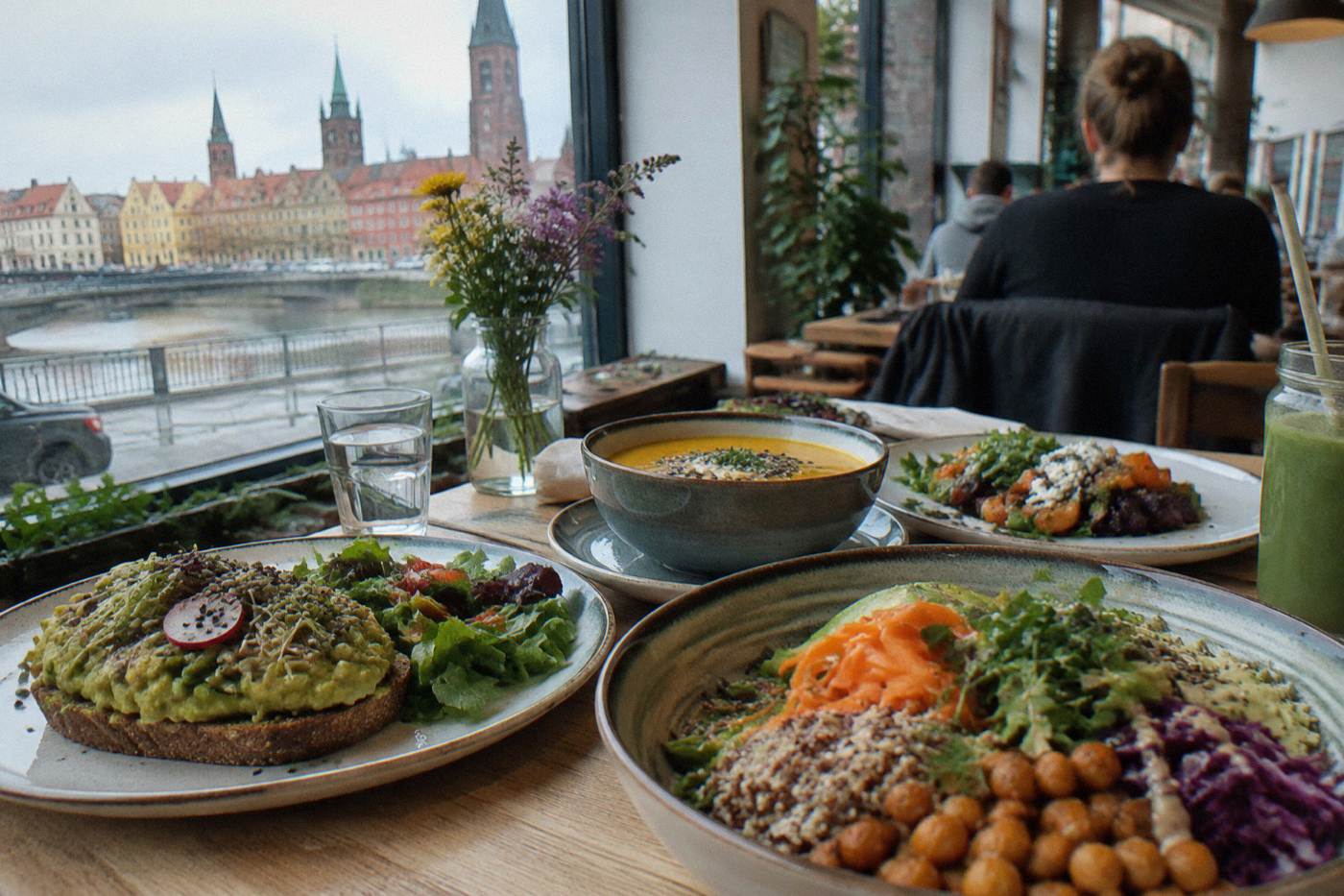 A table of colorful plant-based dishes at a bright restaurant in Wroclaw