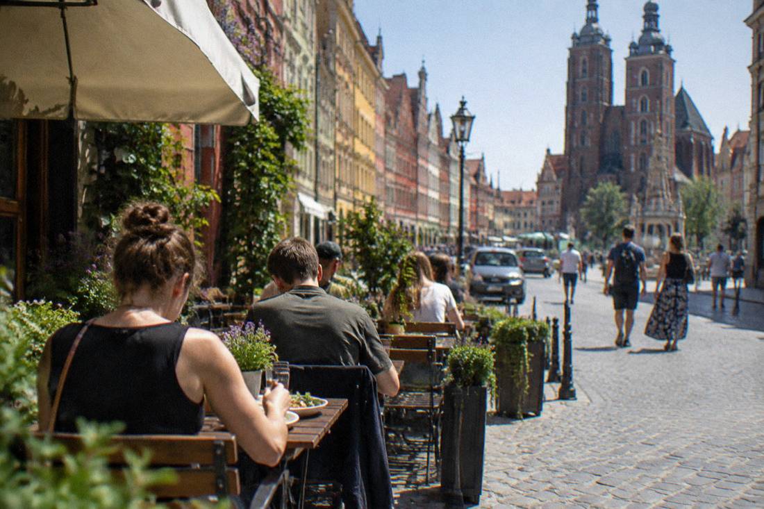 Diners eating outdoors at a small cafe on a colorful street in Wroclaw